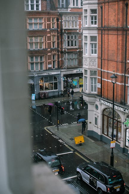 The storefront of Robert Cresser on Marylebone High Street displays a variety of cleaning tools and equipment arranged outside, including traditional straw and bristle brushes with long wooden handles, some with cloth or bristle heads hanging for display. The shop's large glass window showcases a well-maintained interior with warm lighting, highlighting cleaning or home decor items, while the exterior features a dark wood frame with clear signage. The surrounding street scene includes pedestrians and a parked car, with neighboring shop signs visible, reflecting a clean and inviting commercial retail environment consistent with professional cleaning standards promoted by Carpet Cleaning W1 for surface and deep cleaning of shop fronts and interiors.